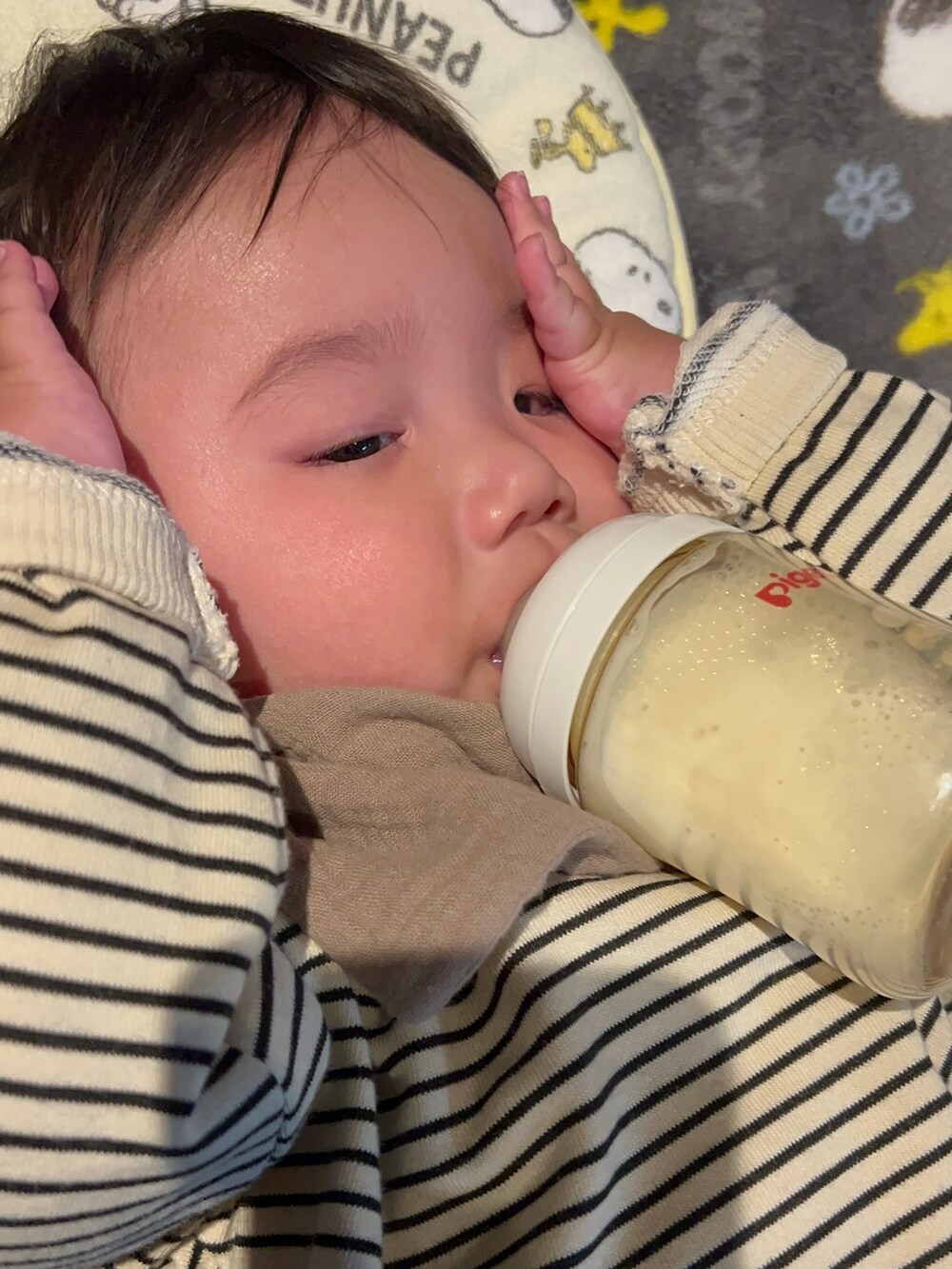 ベージュ系のスウェット、ベージュ系のパンツ、ブルー系のスタイ/よだれかけを着用したキッズの冬コーディネートの2枚目の写真
