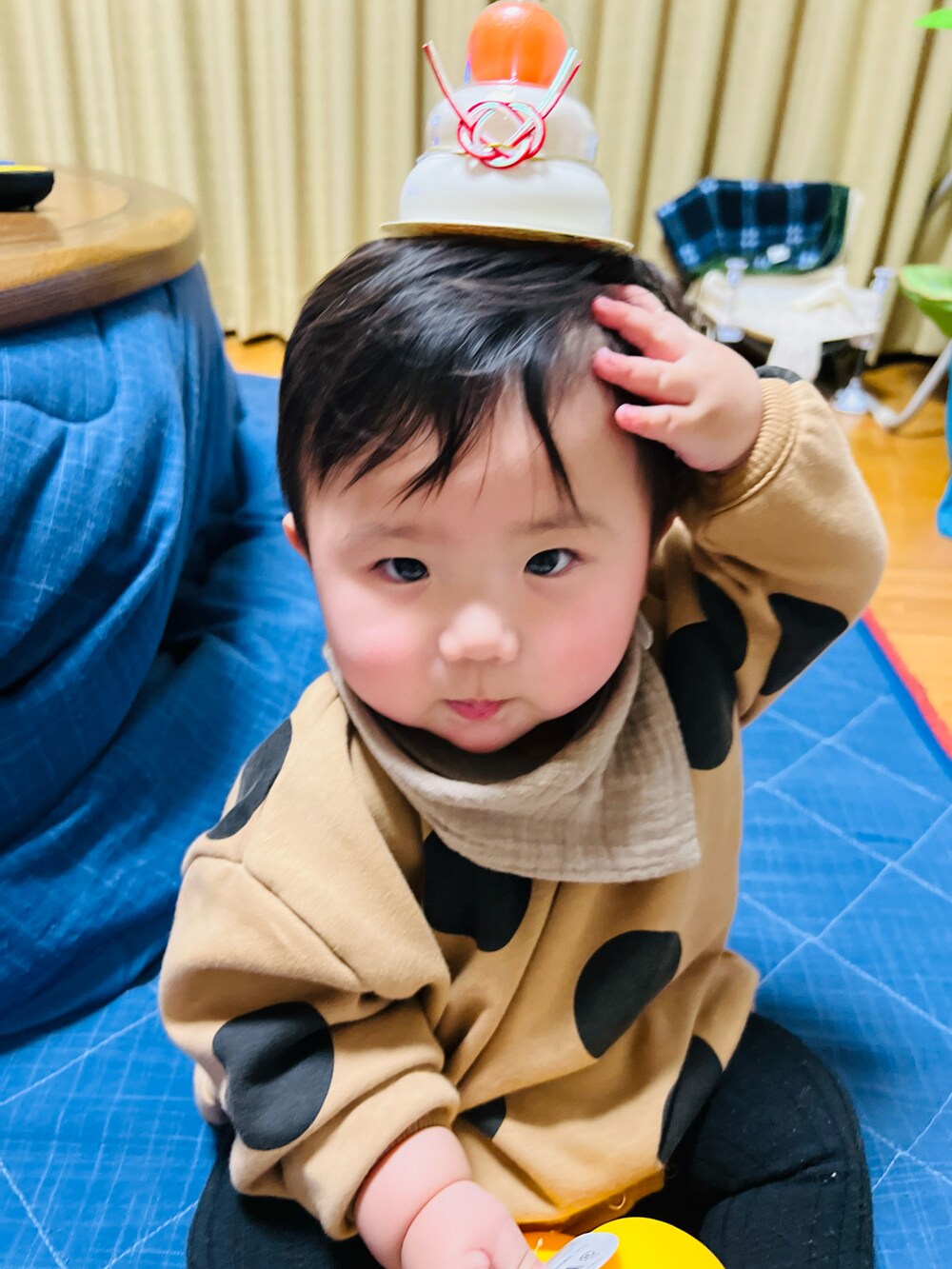 ブラウン系のスタイ/よだれかけ、ブラウン系のロンパース、ブラック系のベビーシューズ/ベビーソックスを着用したキッズの冬コーディネートの2枚目の写真