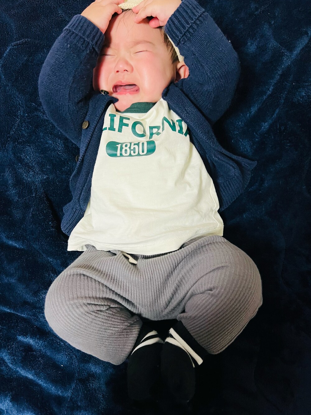 グレー系のパンツ、ホワイト系のTシャツ/カットソー、ブルー系のニット/セーターを着用したキッズの冬コーディネートの2枚目の写真