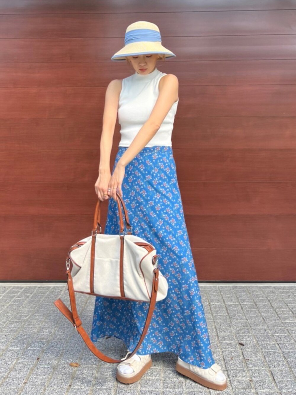 ホワイト系のタンクトップ、ホワイト系のボストンバッグ、ブルー系のスカートを着用したレディースの夏コーディネートの2枚目の写真
