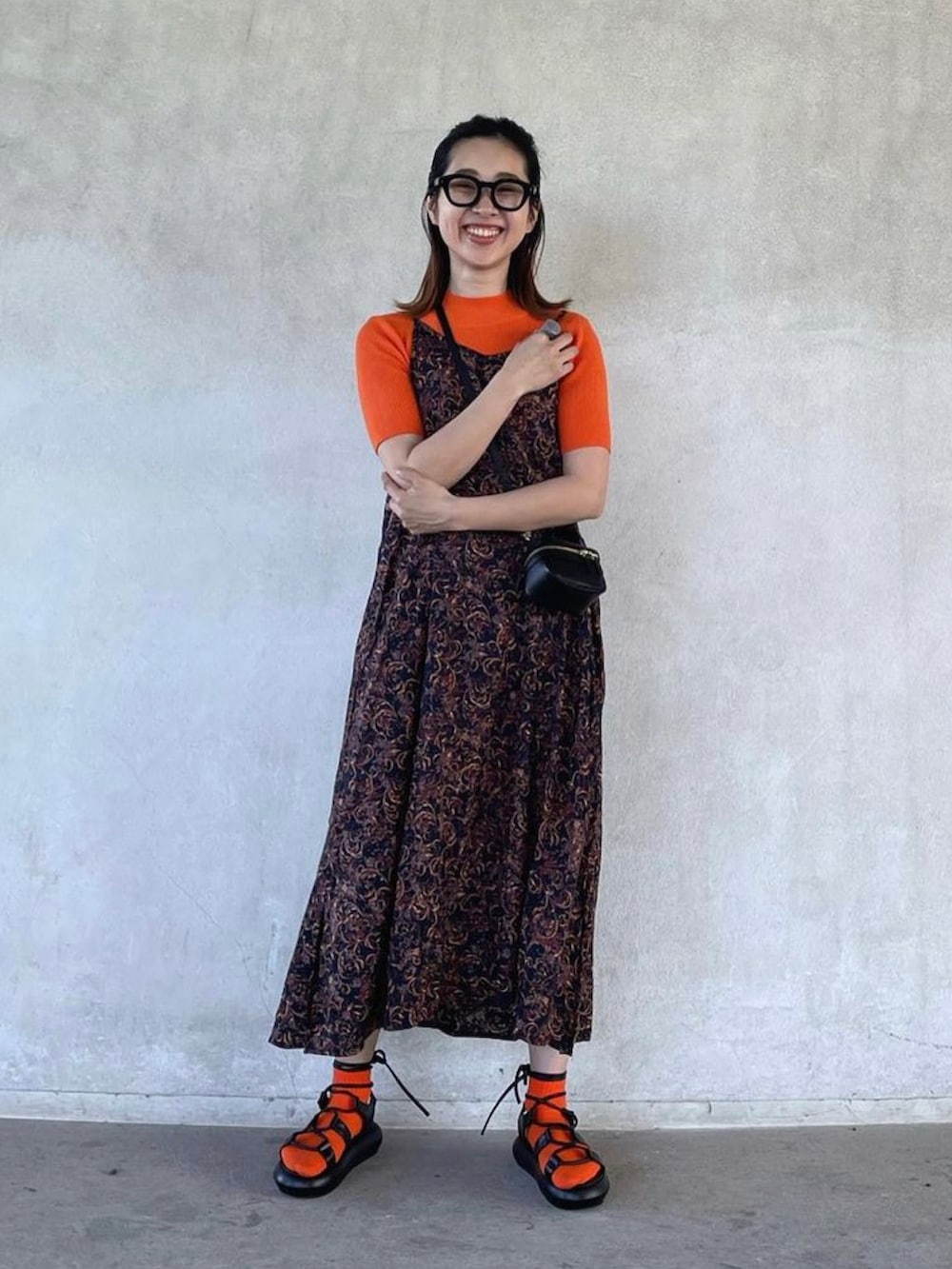 オレンジ系のTシャツ/カットソー、ブラック系のサンダルを着用したレディースの春コーディネートの3枚目の写真