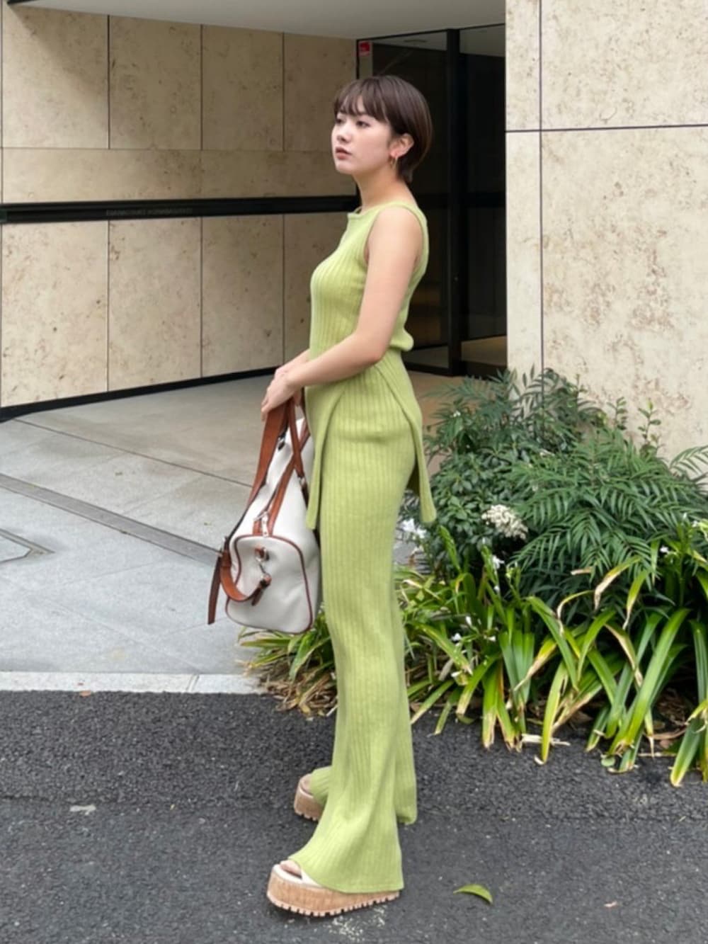 グリーン系のタンクトップ、ベージュ系のサンダル、ホワイト系のボストンバッグを着用したレディースの夏コーディネートの2枚目の写真