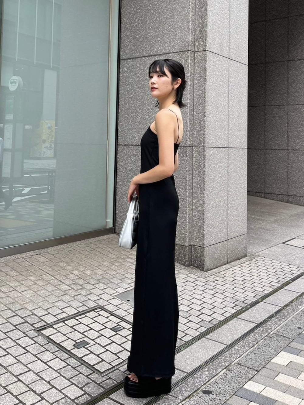 ブラック系のサンダル、シルバー系のハンドバッグ、ブラック系のワンピースを着用したレディースの夏コーディネートの2枚目の写真