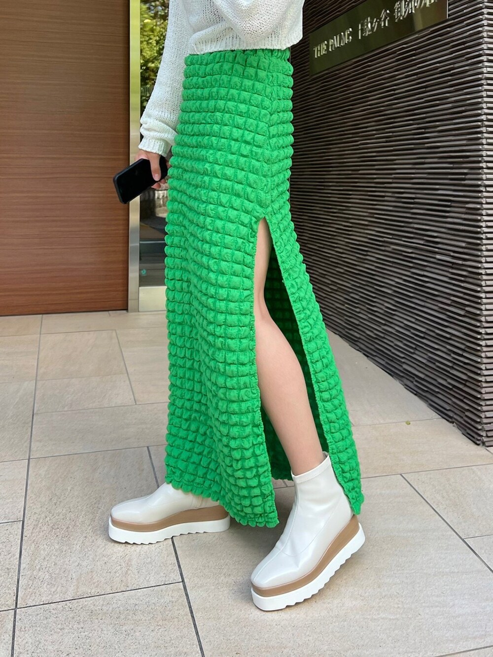 ホワイト系のトップス、グリーン系のスカート、ホワイト系のブーツを着用したレディースの秋コーディネートの2枚目の写真