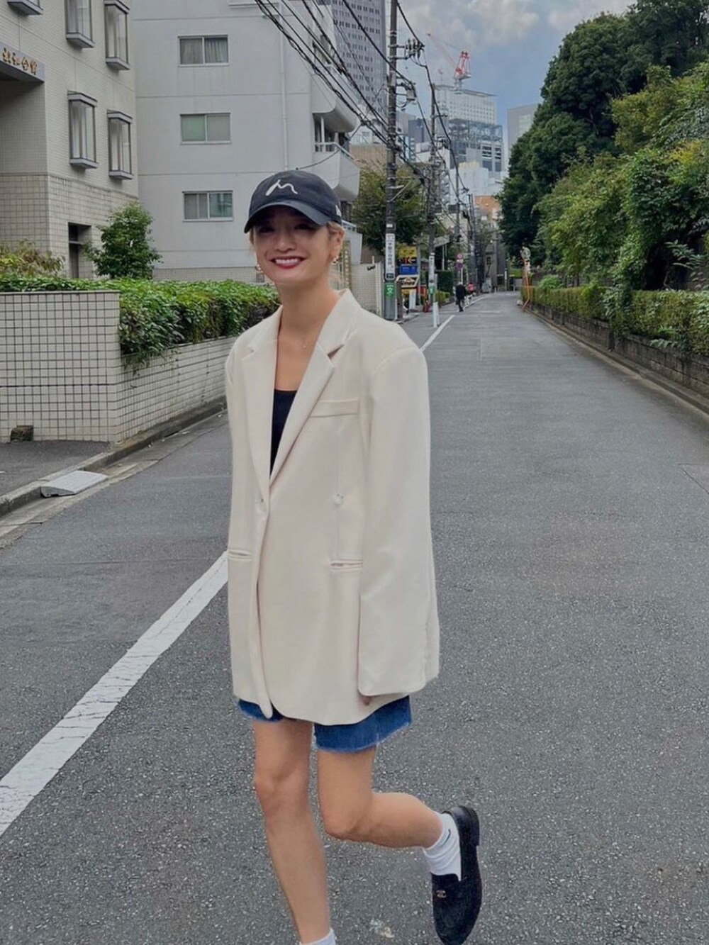 ホワイト系のテーラードジャケット、ブルー系のデニムパンツを着用したレディースの秋コーディネートの2枚目の写真