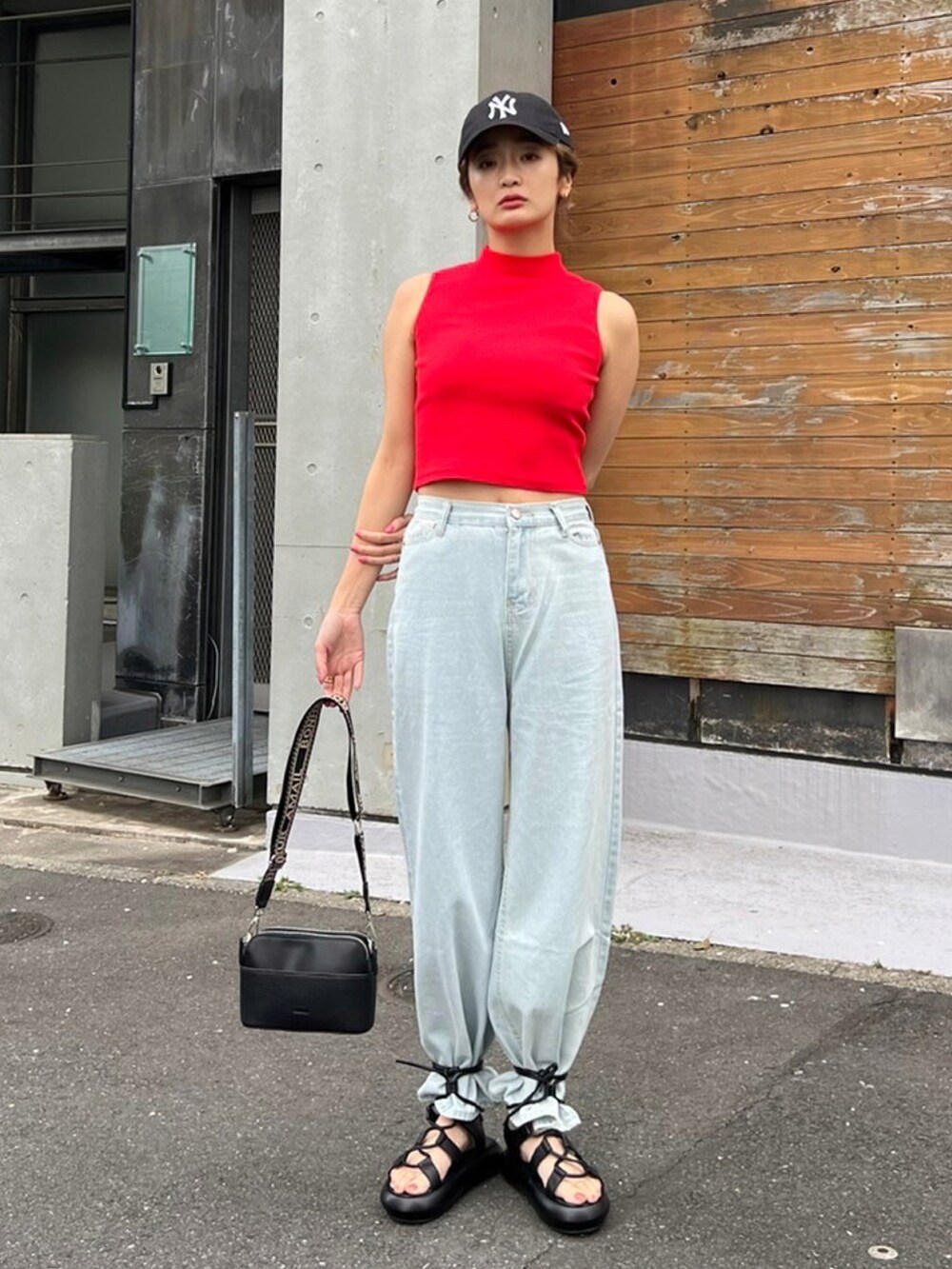 レッド系のタンクトップ、ブラック系のショルダーバッグ、ブラック系のサンダルを着用したレディースの春コーディネートの2枚目の写真