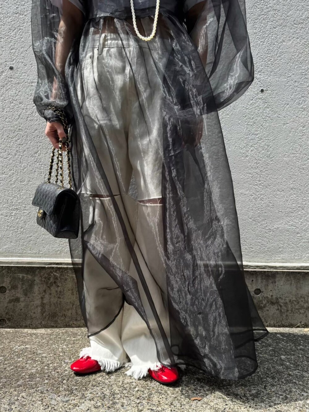 ブラック系のワンピース、ホワイト系のデニムパンツを着用したレディースの夏コーディネートの3枚目の写真