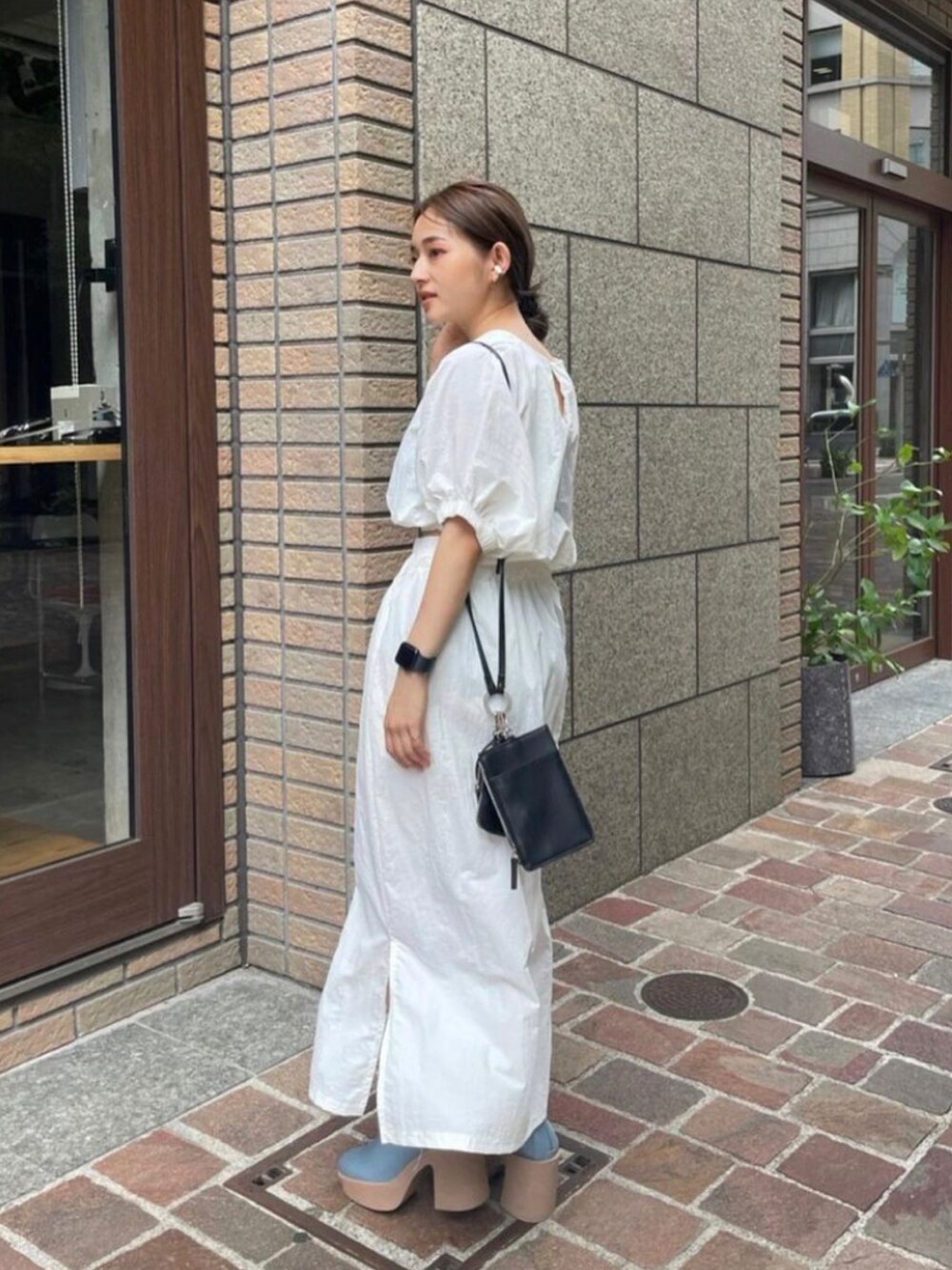 ブラック系のショルダーバッグ、ホワイト系のシャツ/ブラウス、ブルー系のブーツを着用したレディースの秋コーディネートの2枚目の写真