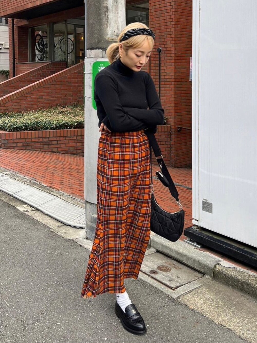 ブラック系のニット/セーター、オレンジ系のスカート、ブラック系のカチューシャを着用したレディースの秋コーディネートの2枚目の写真