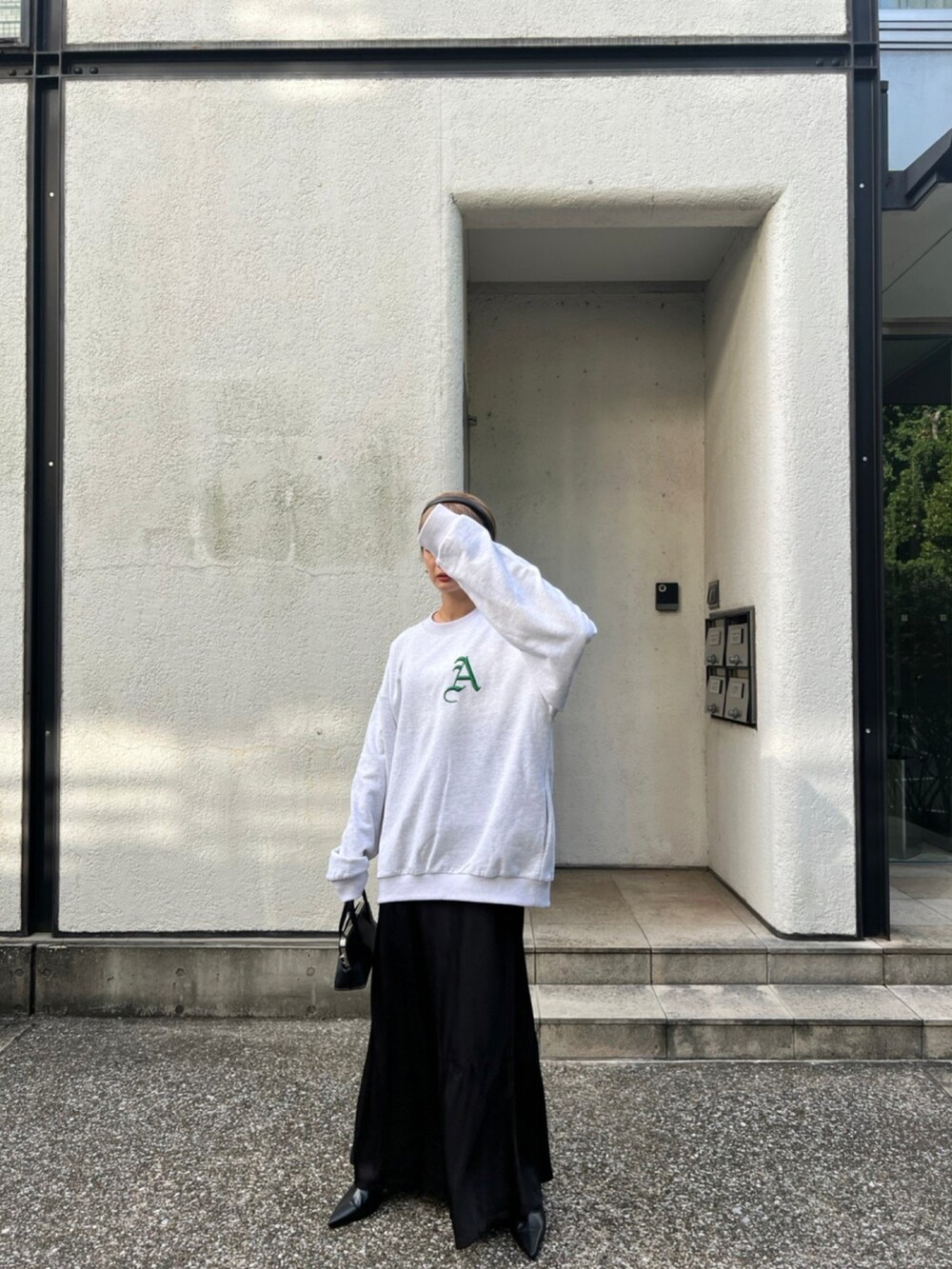 ブラック系のショルダーバッグ、グレー系のスウェット、ブラック系のスカートを着用したレディースの秋コーディネートの2枚目の写真