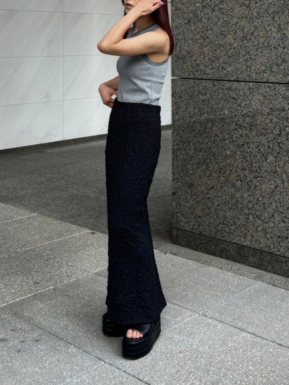 グレー系のタンクトップ、ブラック系のスカート、ブラック系のサンダルを着用したレディースの夏コーディネートの2枚目の写真