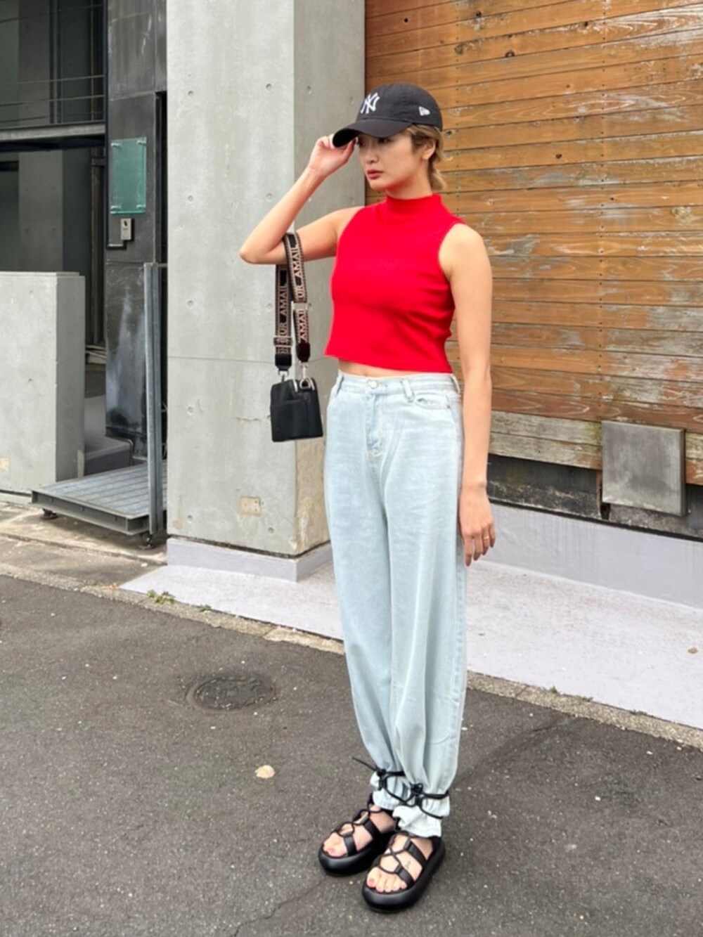 レッド系のタンクトップ、ブラック系のショルダーバッグ、ブラック系のサンダルを着用したレディースの春コーディネートの3枚目の写真