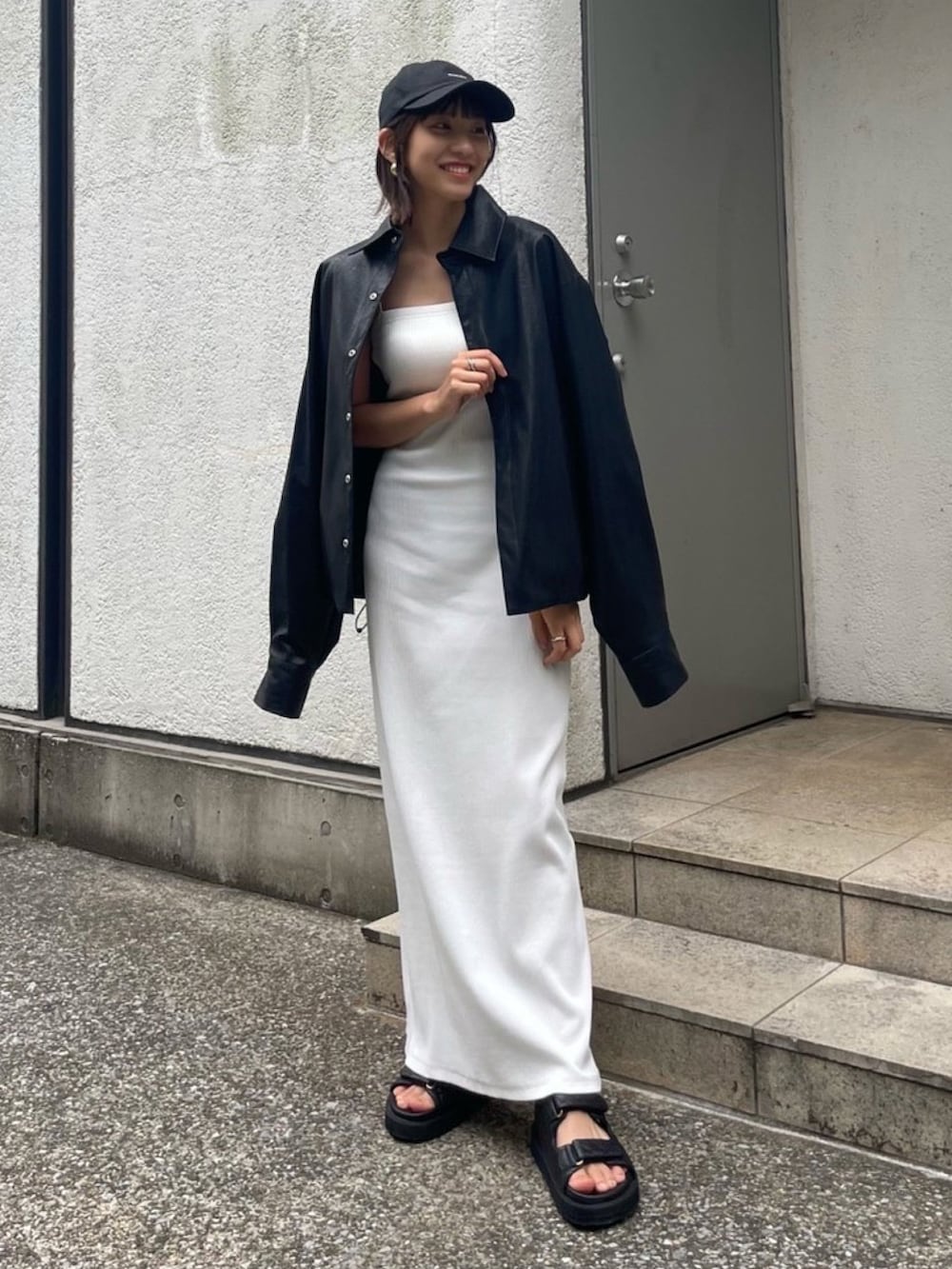 ホワイト系のワンピース、ブラック系のサンダル、ブラック系のキャップを着用したレディースの夏コーディネートの2枚目の写真