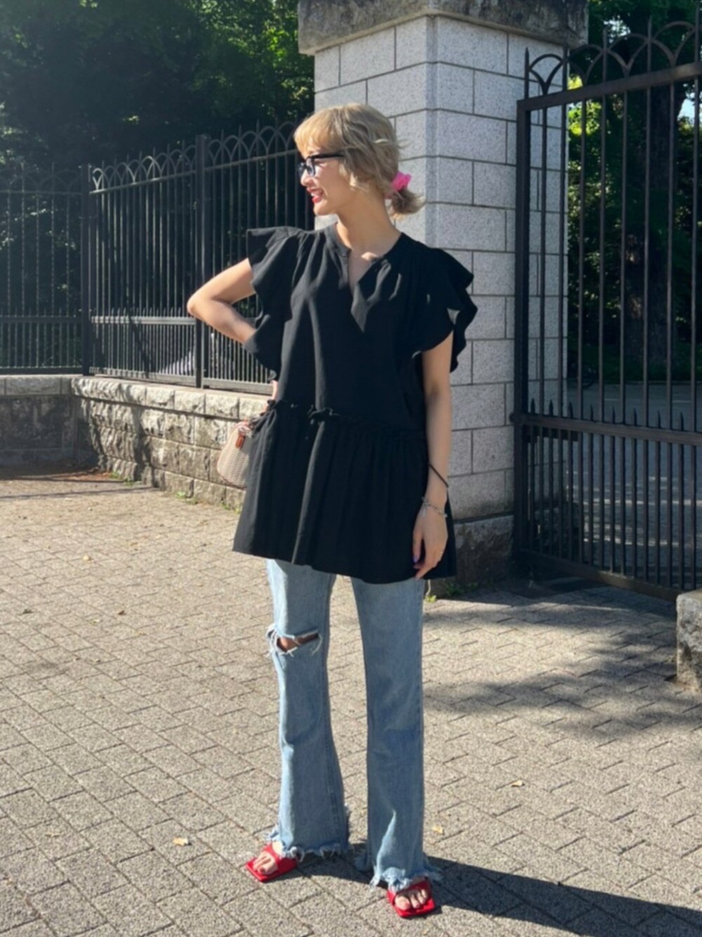 ホワイト系のショルダーバッグ、ブラック系のワンピース、レッド系のサンダルを着用したレディースの春コーディネートの2枚目の写真