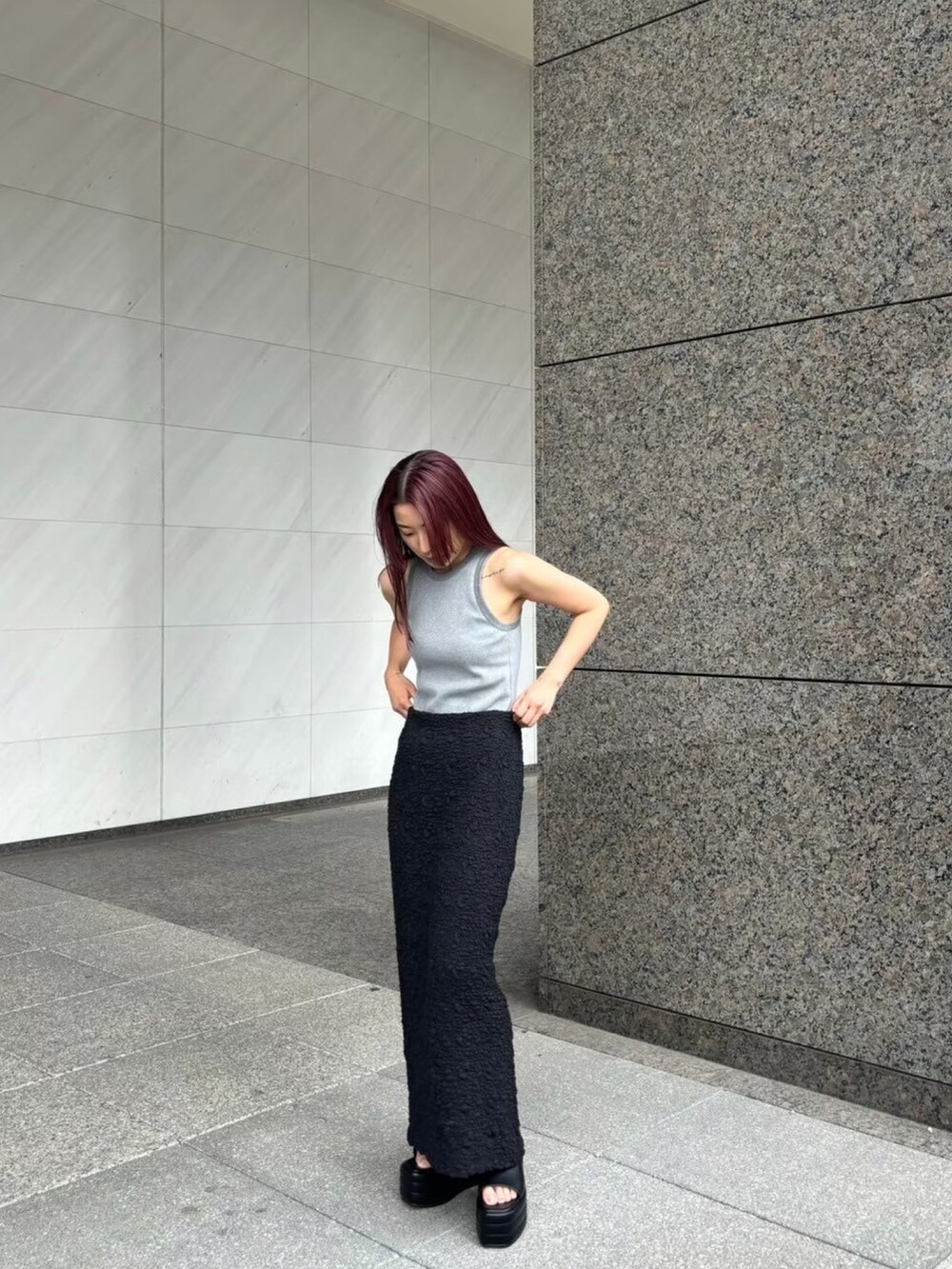 グレー系のタンクトップ、ブラック系のスカート、ブラック系のサンダルを着用したレディースの夏コーディネートの3枚目の写真