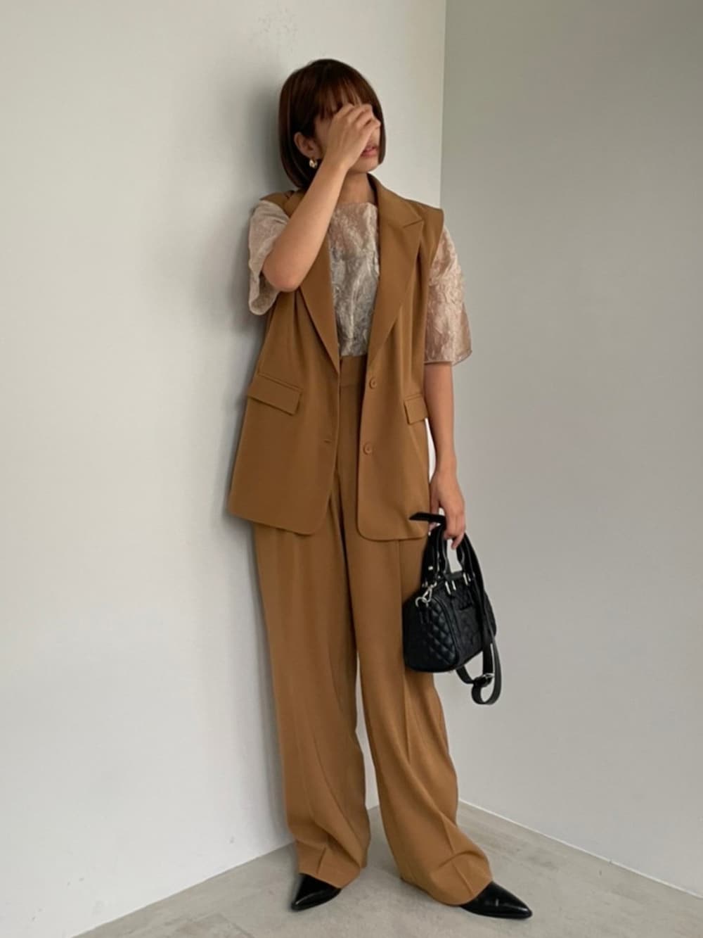 ブラウン系のベスト、ブラック系のショルダーバッグ、ブラウン系のその他パンツを着用したレディースの秋コーディネートの2枚目の写真