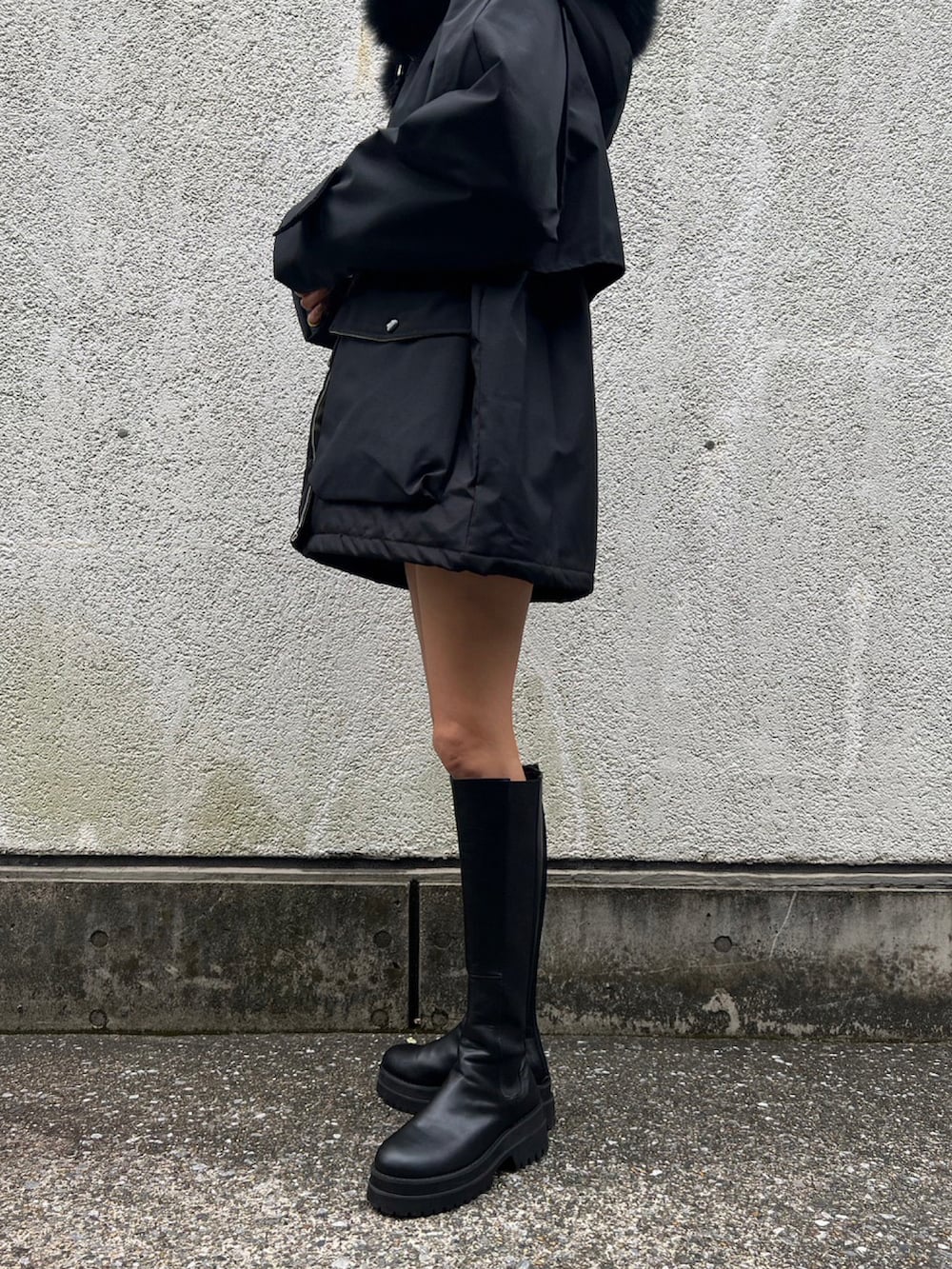 ブラック系のダウンジャケット/コート、ブラック系のブーツ、ブラック系のキャップを着用したレディースの秋コーディネートの2枚目の写真