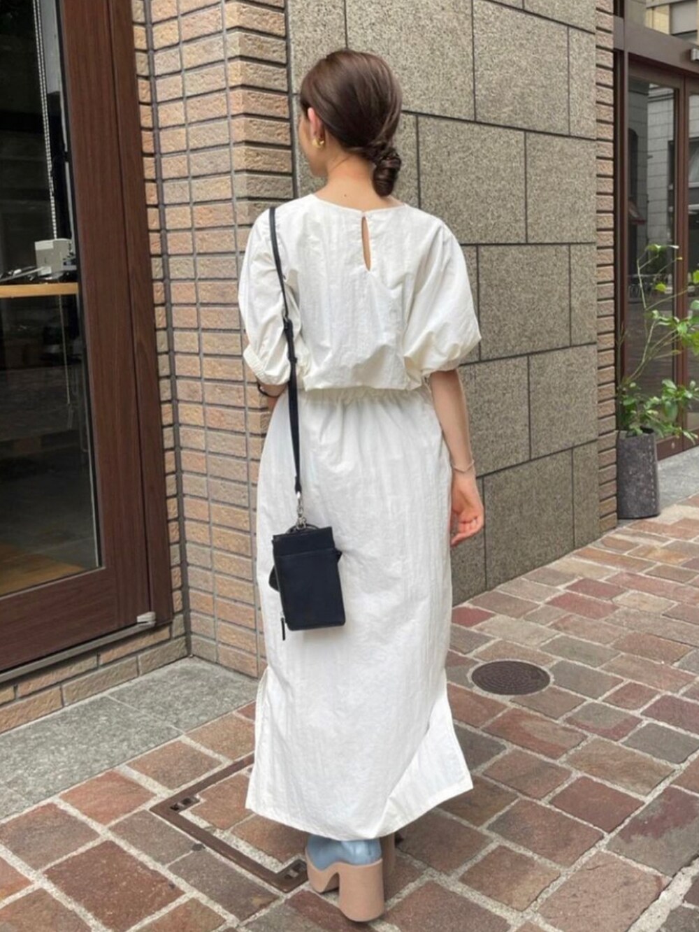 ブラック系のショルダーバッグ、ホワイト系のシャツ/ブラウス、ブルー系のブーツを着用したレディースの秋コーディネートの3枚目の写真