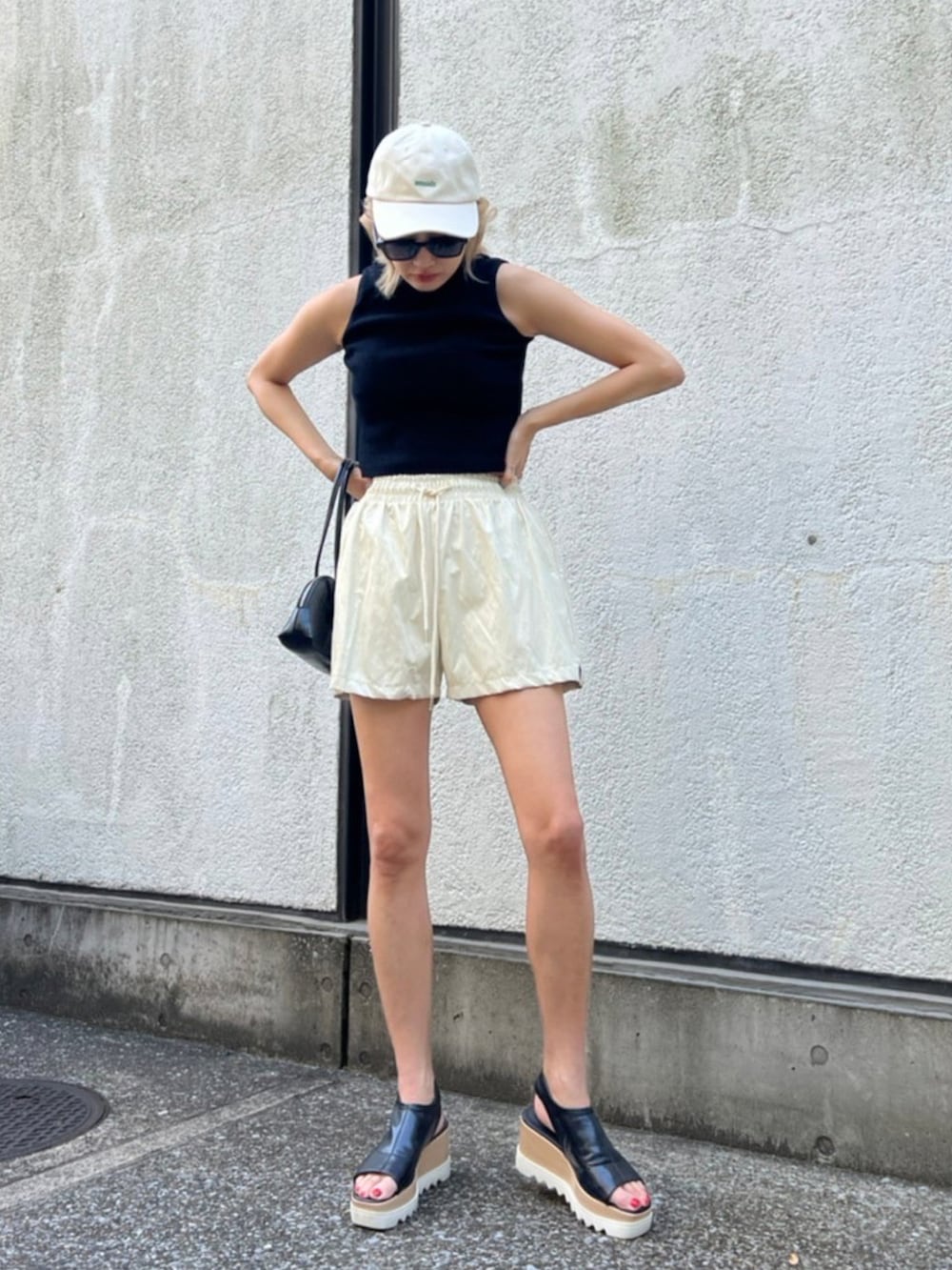 ブラック系のタンクトップ、ブラック系のハンドバッグ、ブラック系のサンダルを着用したレディースの夏コーディネートの2枚目の写真