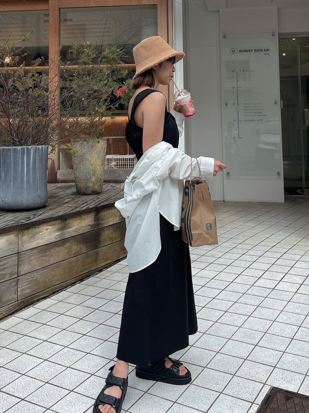 ブラック系のワンピース、ブラック系のサンダル、ベージュ系のハットを着用したレディースの春コーディネートの2枚目の写真