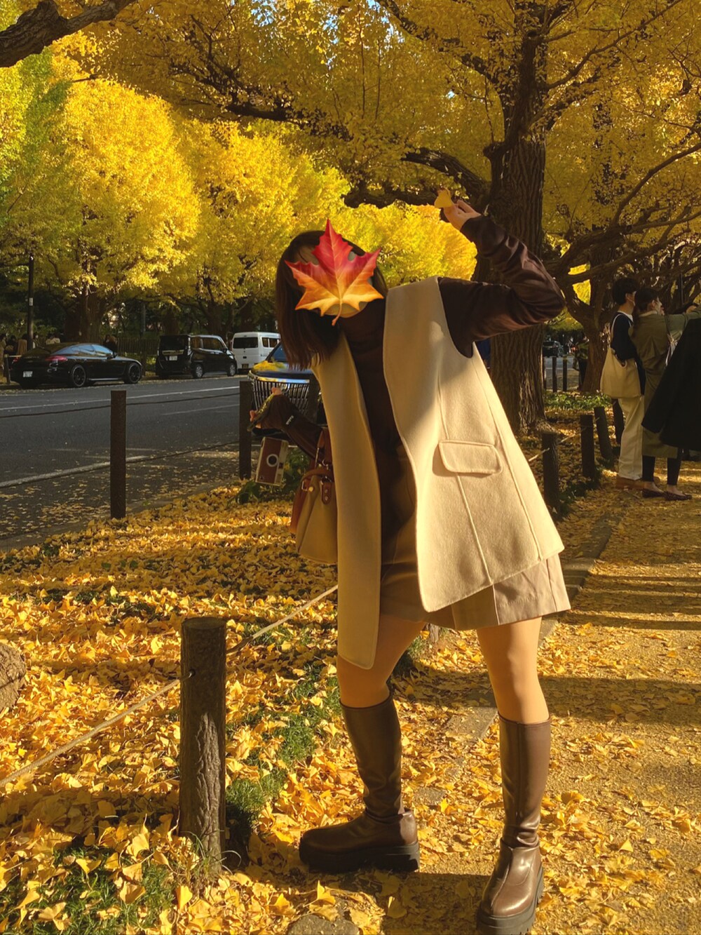 ブラウン系のブーツ、ベージュ系のハンドバッグ、ベージュ系のベストを着用したレディースの秋コーディネートの2枚目の写真