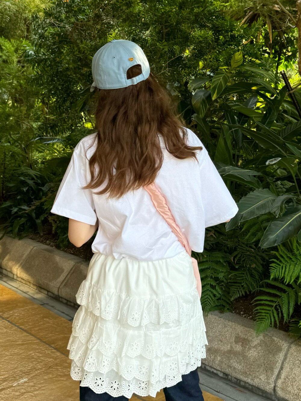 ホワイト系のスカート、ピンク系のショルダーバッグ、ブルー系のデニムパンツを着用したレディースの夏コーディネートの2枚目の写真