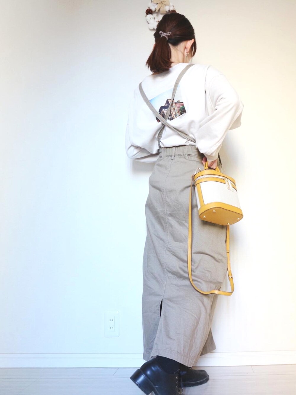 イエロー系のショルダーバッグ、ベージュ系のスカート、ブラック系のブーツを着用したレディースの冬コーディネートの2枚目の写真