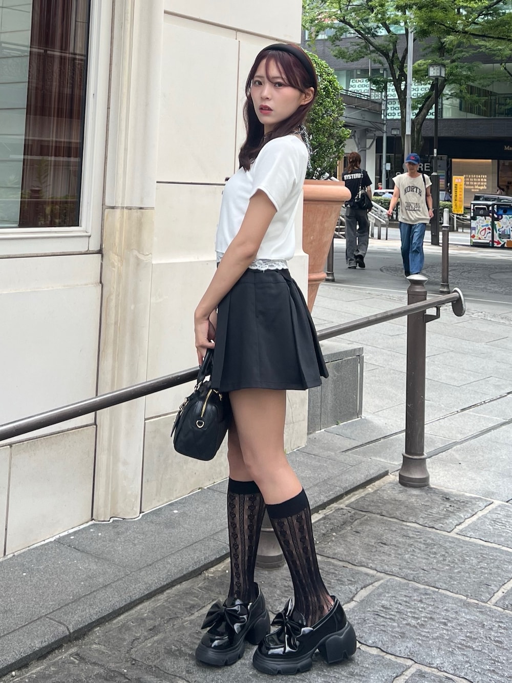 ホワイト系のTシャツ/カットソー、ブラック系のスカート、ブラック系のボストンバッグを着用したレディースの夏コーディネートの3枚目の写真