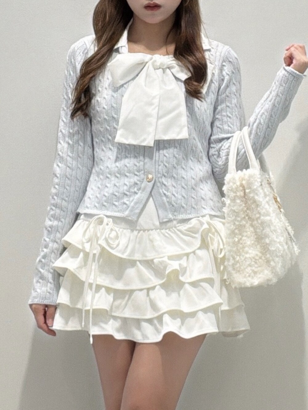 ブルー系のニット/セーター、ホワイト系のスカート、ブラック系のブーツを着用したレディースの冬コーディネートの2枚目の写真