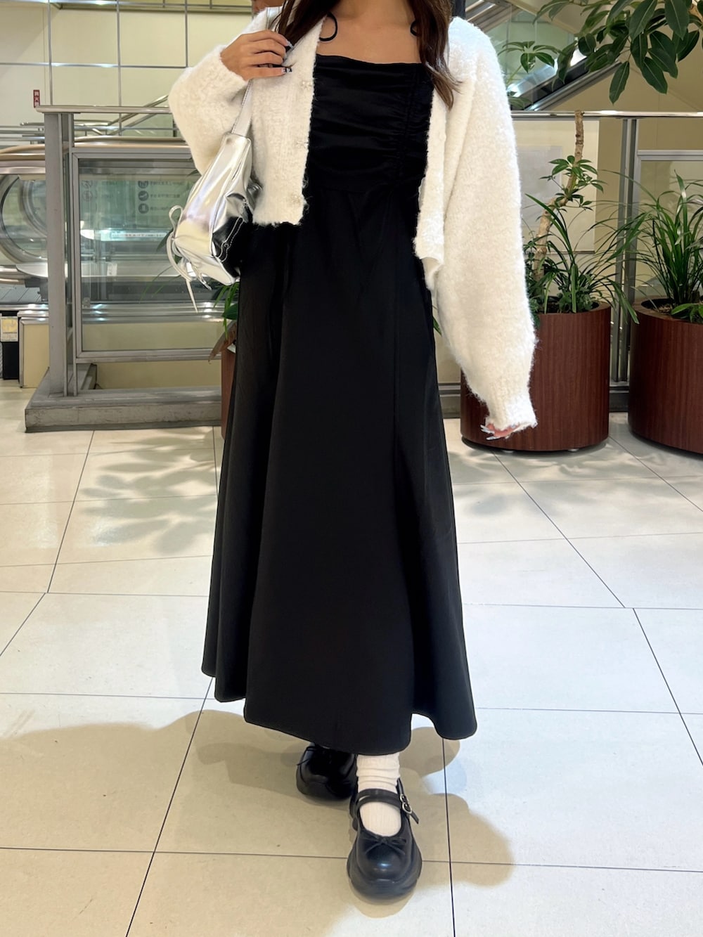 ブラック系のワンピース、ホワイト系のカーディガン/ボレロ、シルバー系のショルダーバッグを着用したレディースの秋コーディネートの3枚目の写真