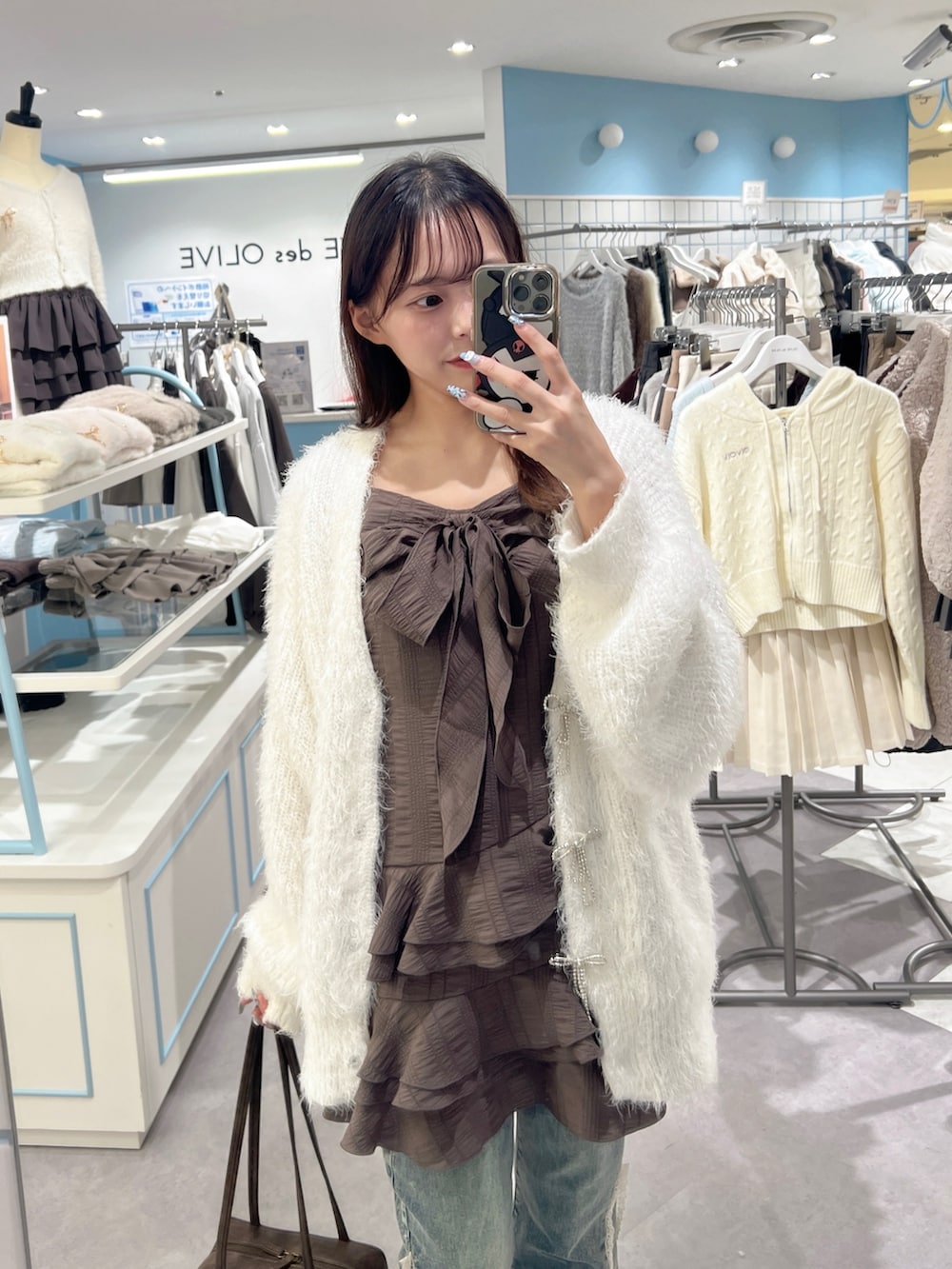 ホワイト系のカーディガン/ボレロ、ブラウン系のワンピース、ブルー系のデニムパンツを着用したレディースの秋コーディネートの4枚目の写真