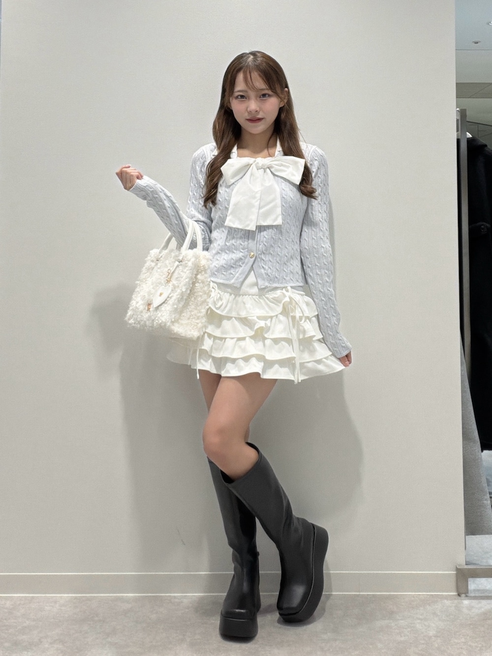 ブルー系のニット/セーター、ホワイト系のスカート、ブラック系のブーツを着用したレディースの冬コーディネートの3枚目の写真