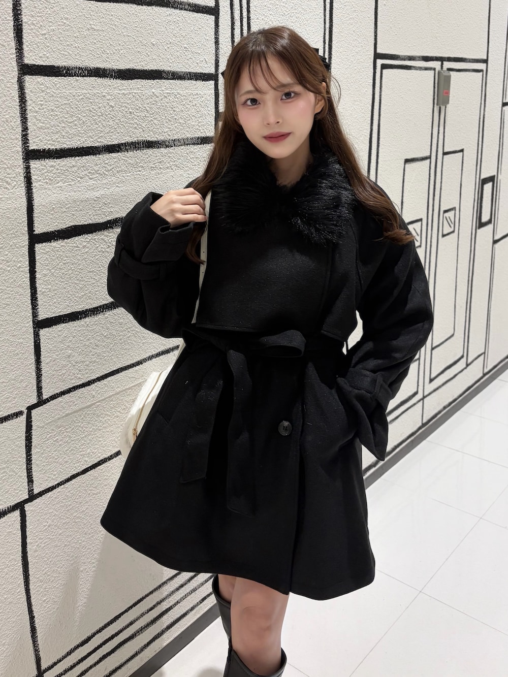 ブラック系のステンカラーコート、ブラック系のブーツを着用したレディースの秋コーディネートの2枚目の写真