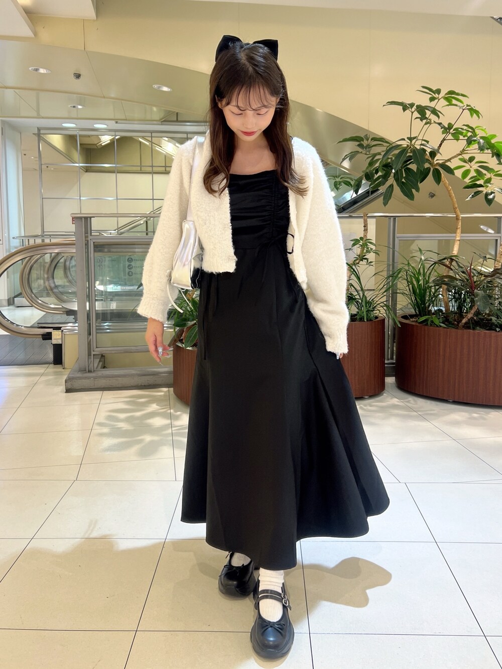 ブラック系のワンピース、ホワイト系のカーディガン/ボレロ、シルバー系のショルダーバッグを着用したレディースの秋コーディネートの4枚目の写真