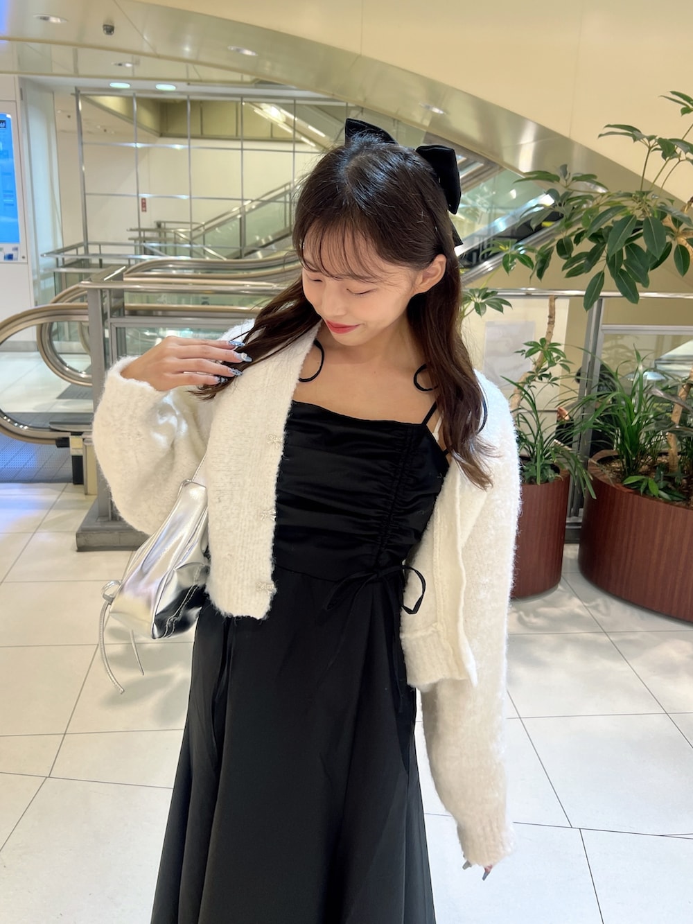 ブラック系のワンピース、ホワイト系のカーディガン/ボレロ、シルバー系のショルダーバッグを着用したレディースの秋コーディネートの2枚目の写真