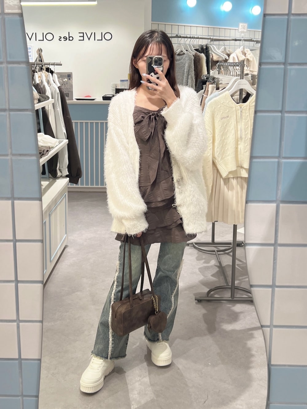 ホワイト系のカーディガン/ボレロ、ブラウン系のワンピース、ブルー系のデニムパンツを着用したレディースの秋コーディネートの5枚目の写真