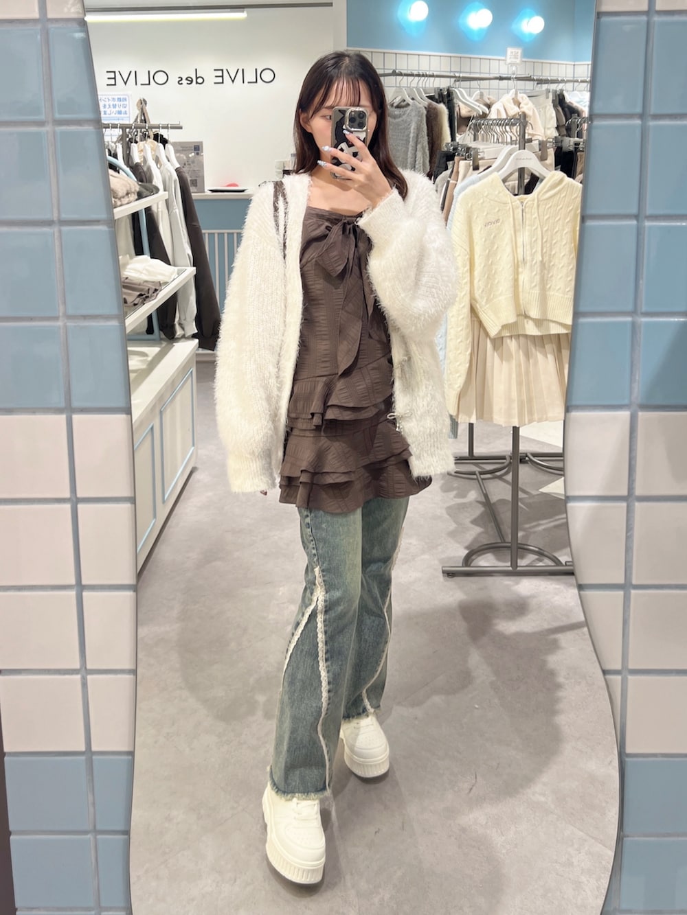 ホワイト系のカーディガン/ボレロ、ブラウン系のワンピース、ブルー系のデニムパンツを着用したレディースの秋コーディネートの3枚目の写真