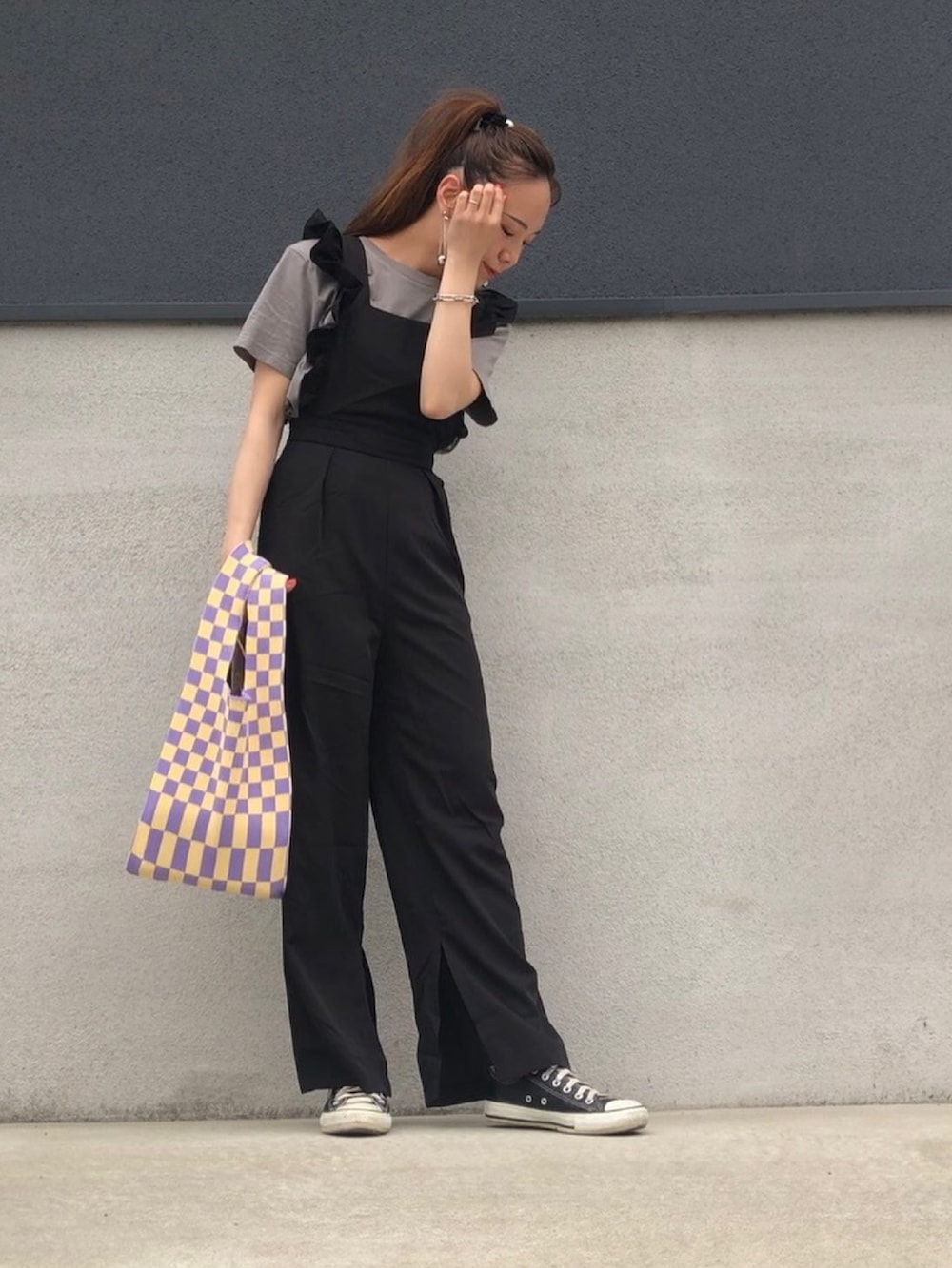 ブラック系のサロペット/オーバーオール、イエロー系のトートバッグ、グレー系のTシャツ/カットソーを着用したレディースの春コーディネートの3枚目の写真