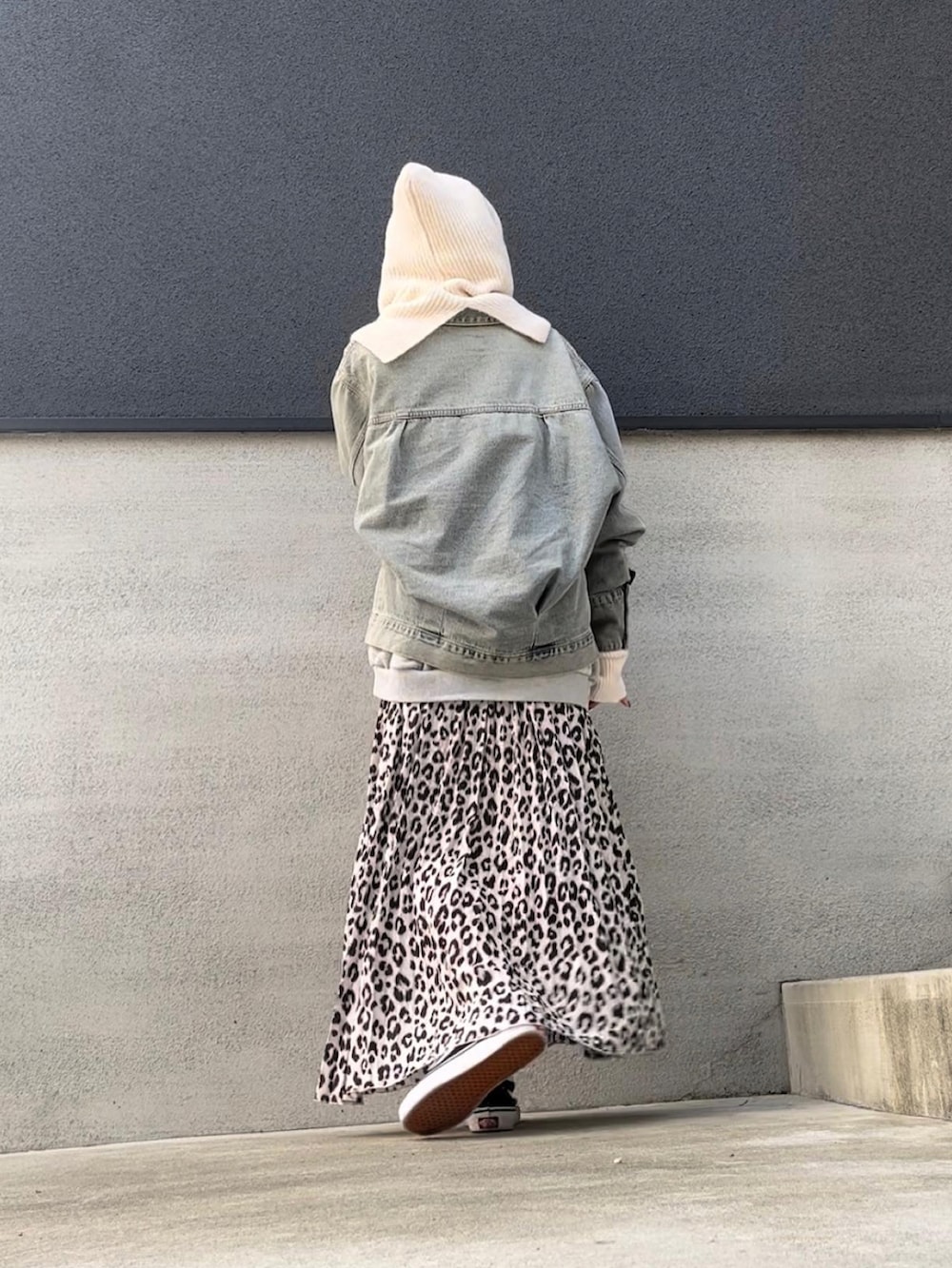 ホワイト系のスカート、ブルー系のデニムジャケット、ブラック系のスニーカーを着用したレディースの秋コーディネートの2枚目の写真