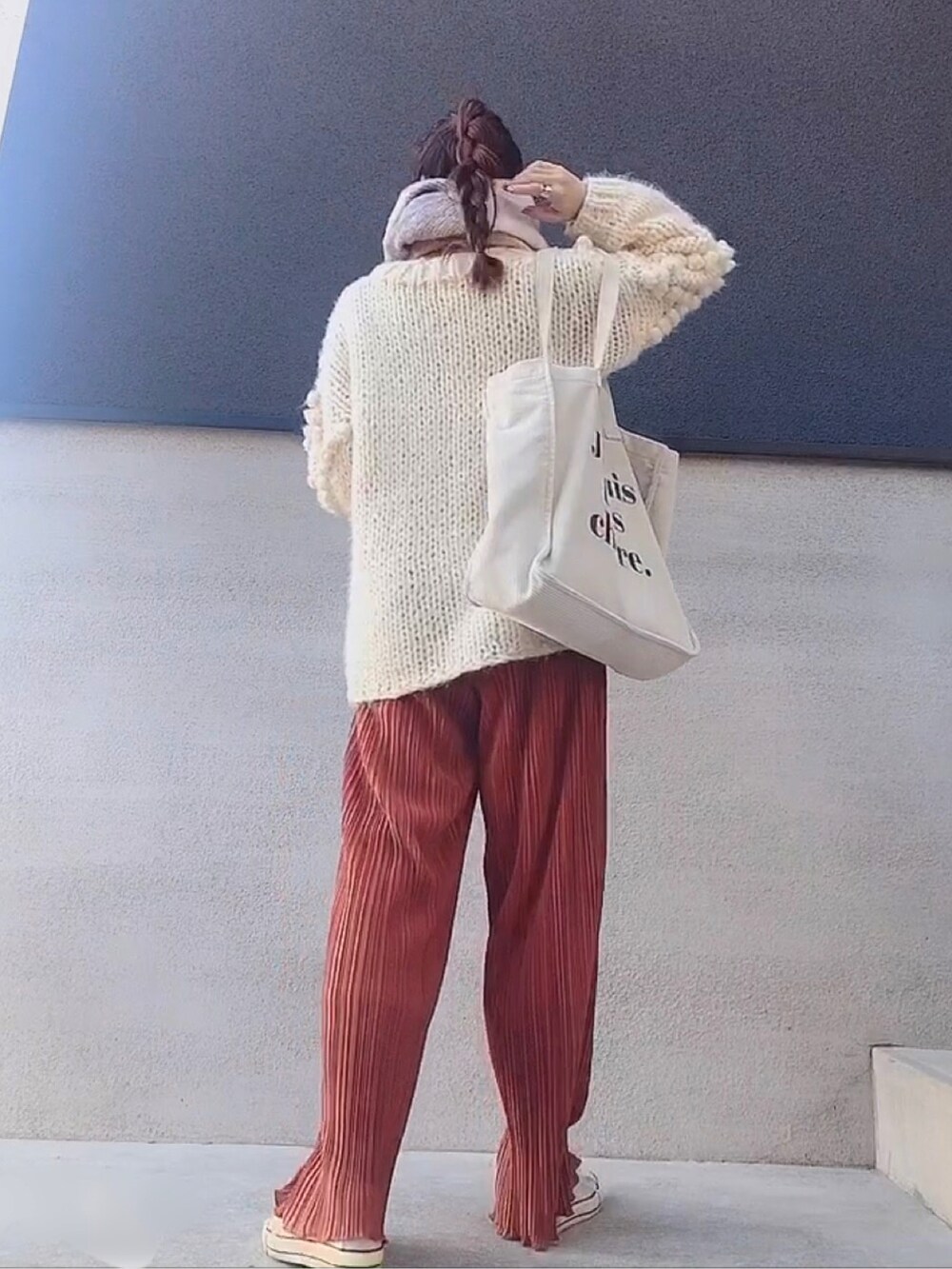 ホワイト系のトートバッグ、オレンジ系のパンツ、ホワイト系のニット/セーターを着用したレディースの冬コーディネートの2枚目の写真