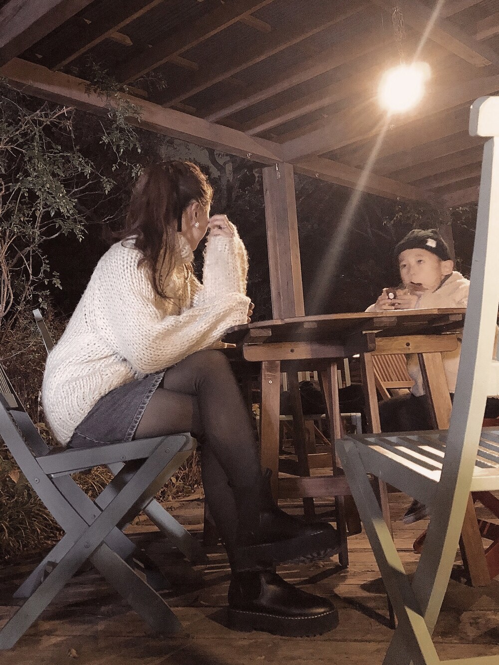 ホワイト系のニット/セーター、ブルー系のデニムスカート、ブラック系のブーツを着用したレディースの秋コーディネートの2枚目の写真