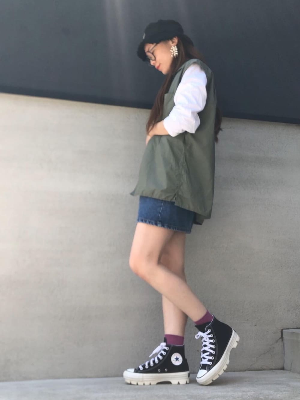 ブルー系のデニムスカート、ブラック系のスニーカー、グリーン系のベストを着用したレディースの夏コーディネートの2枚目の写真