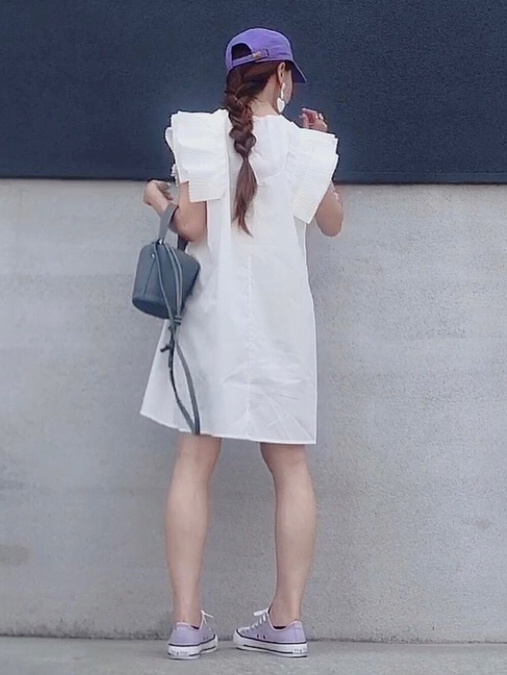 ホワイト系のトップス、ブルー系のハンドバッグ、パープル系のスニーカーを着用したレディースの夏コーディネートの2枚目の写真