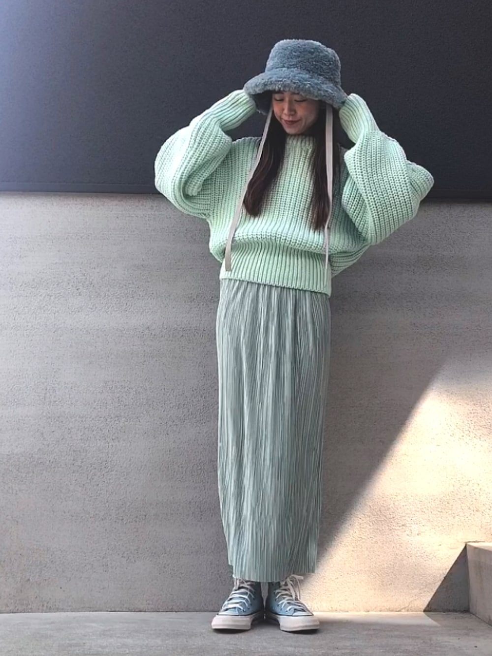 グリーン系のスカート、グリーン系のニット/セーター、ブルー系のスニーカーを着用したレディースの冬コーディネートの2枚目の写真