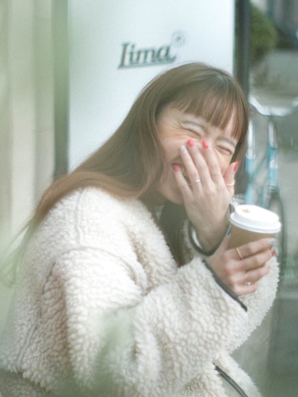 ホワイト系のノーカラーコート、ホワイト系のスカート、ベージュ系のスニーカーを着用したレディースの冬コーディネートの2枚目の写真