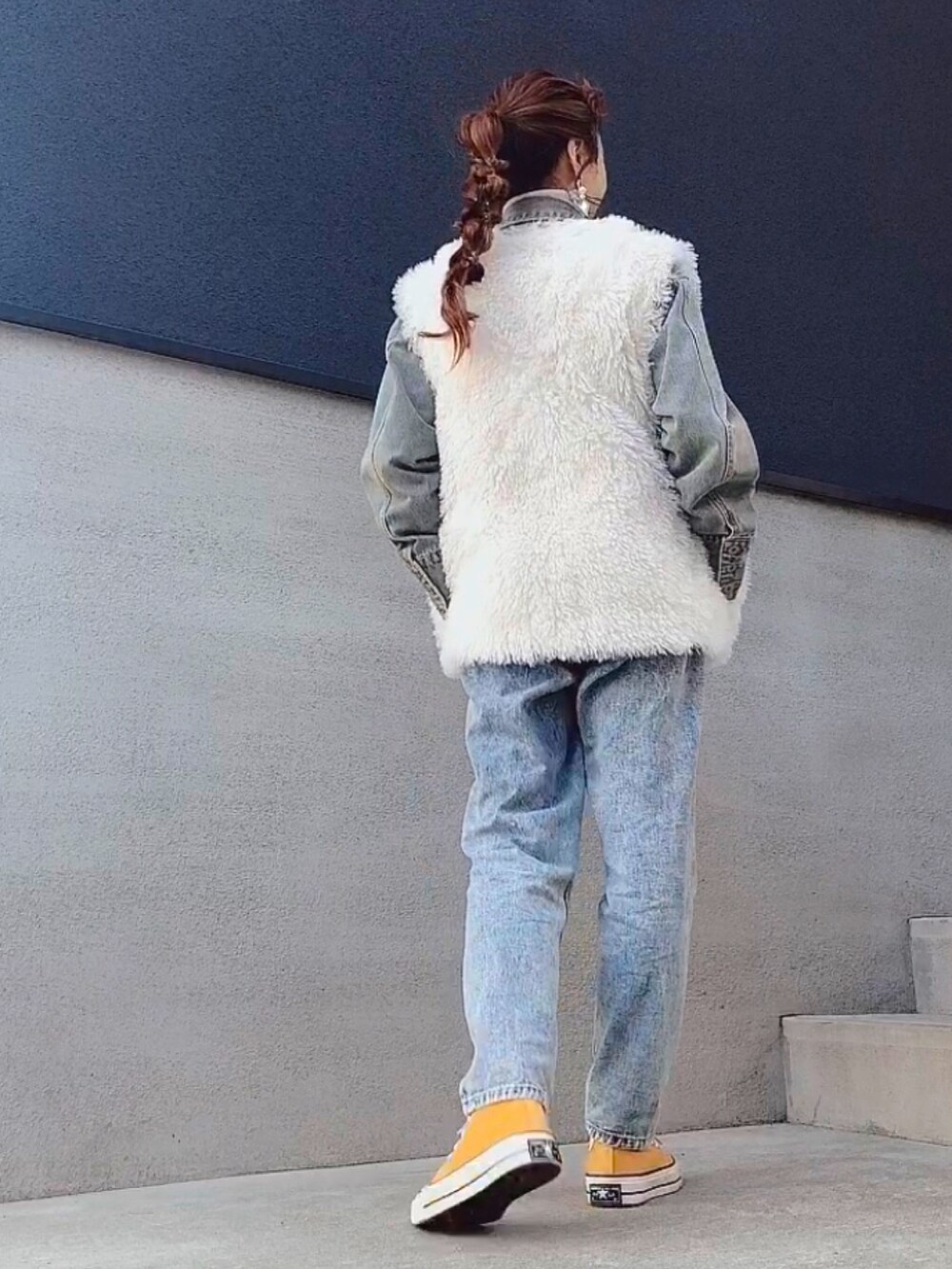 ブルー系のデニムパンツ、イエロー系のスニーカー、ホワイト系のベストを着用したレディースの冬コーディネートの2枚目の写真