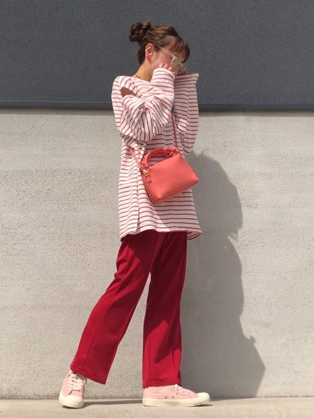 レッド系のパンツ、ピンク系のスニーカー、レッド系のTシャツ/カットソーを着用したレディースの春コーディネートの3枚目の写真