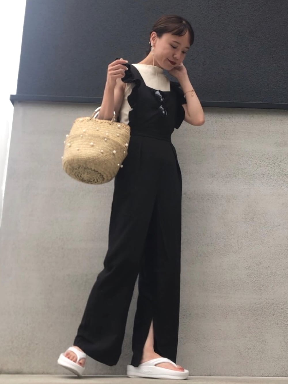 ベージュ系のかごバッグ、ブラック系のサロペット/オーバーオール、ホワイト系のサンダルを着用したレディースの夏コーディネートの2枚目の写真
