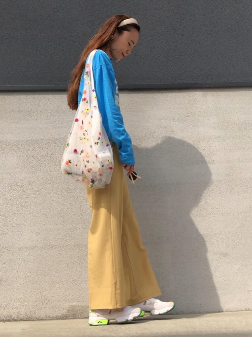 イエロー系のその他パンツ、ブルー系のTシャツ/カットソー、ホワイト系のスニーカーを着用したレディースの春コーディネートの2枚目の写真