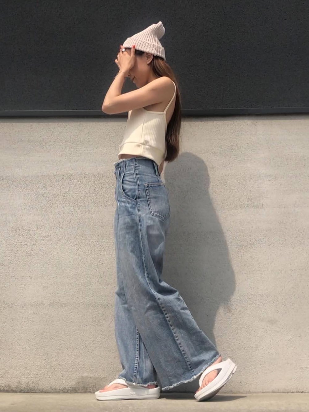 ブルー系のデニムパンツ、ホワイト系のキャミソール、ホワイト系のサンダルを着用したレディースの夏コーディネートの2枚目の写真